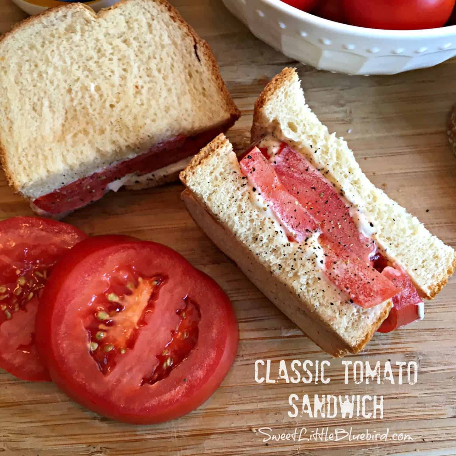 tomato sandwich on cutting board with slices of tomatoes